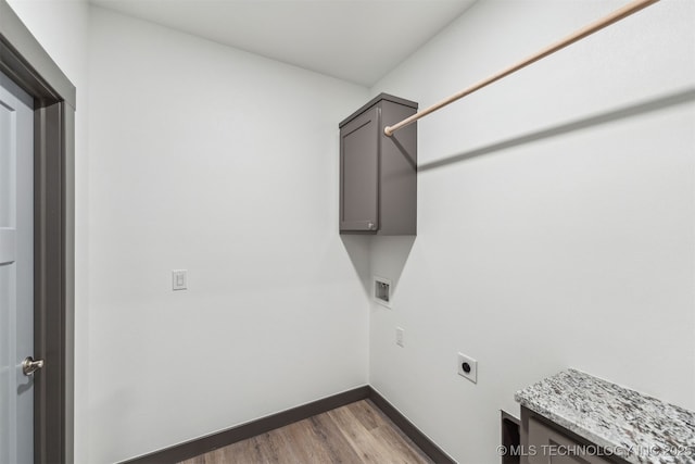 laundry room with cabinet space, hookup for an electric dryer, baseboards, and wood finished floors