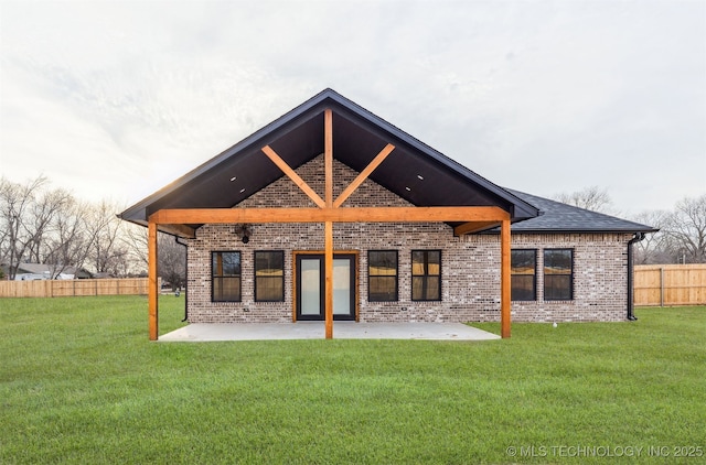 rear view of house featuring brick siding, a yard, a shingled roof, a patio area, and fence