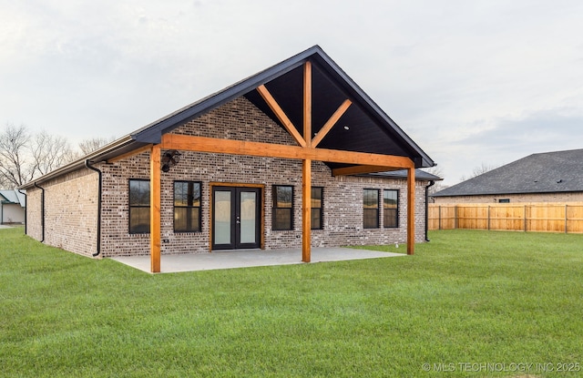 back of house featuring brick siding, a patio, a lawn, and fence