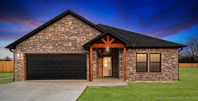 traditional home with a lawn, concrete driveway, roof with shingles, an attached garage, and brick siding