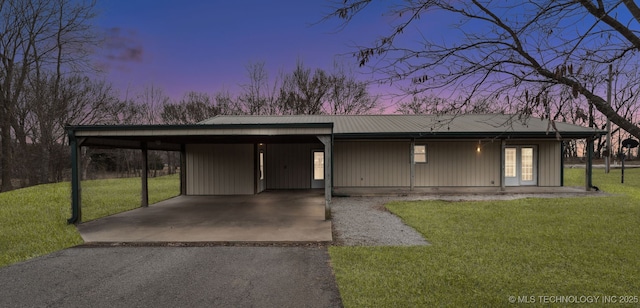 view of front of home with a carport, a yard, aphalt driveway, and metal roof