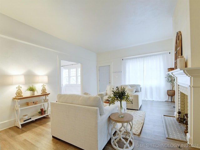 living room with a brick fireplace and light wood-type flooring