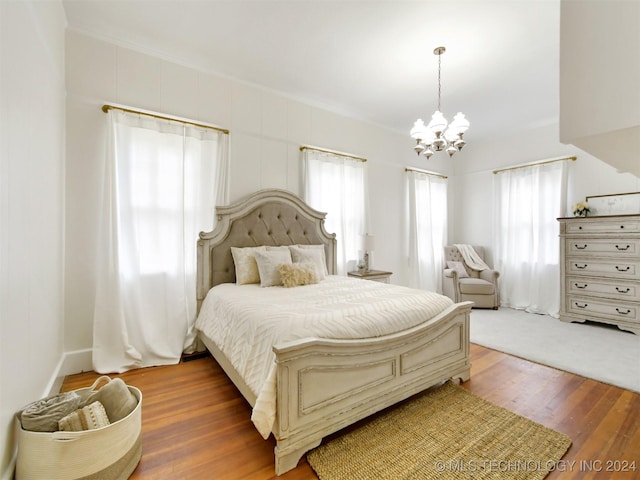 bedroom featuring multiple windows, dark hardwood / wood-style flooring, ornamental molding, and a notable chandelier