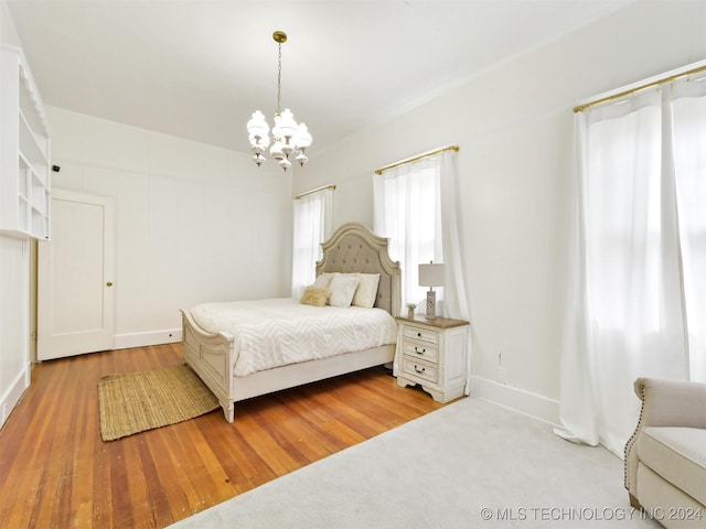 bedroom with light hardwood / wood-style floors and a notable chandelier