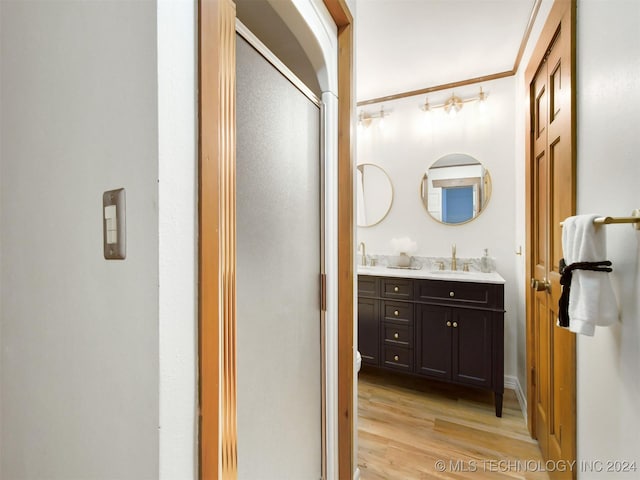 bathroom featuring hardwood / wood-style floors, vanity, a shower with shower door, and ornamental molding