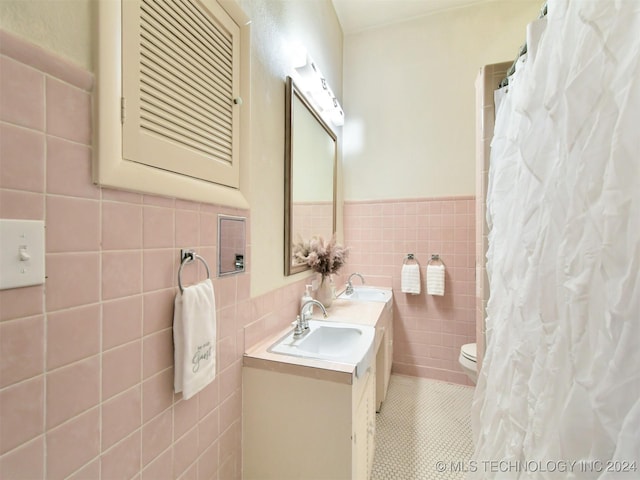 bathroom featuring tile patterned flooring, vanity, toilet, and tile walls