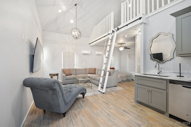 living room with ceiling fan with notable chandelier, light wood-type flooring, sink, and a high ceiling