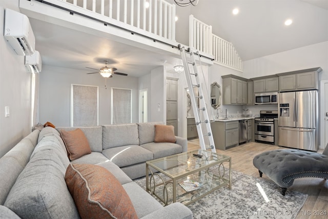 living room with an AC wall unit, light hardwood / wood-style flooring, high vaulted ceiling, and sink