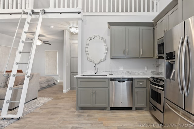 kitchen featuring gray cabinetry, light hardwood / wood-style flooring, stainless steel appliances, and sink