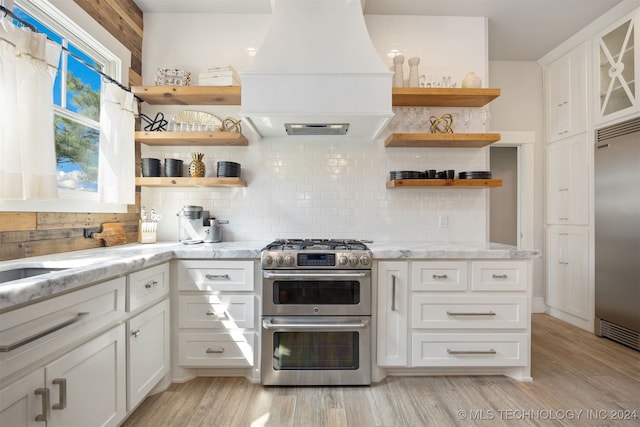 kitchen with decorative backsplash, white cabinetry, custom exhaust hood, and premium appliances