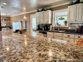 kitchen with sink, dishwasher, dark stone counters, and ornamental molding