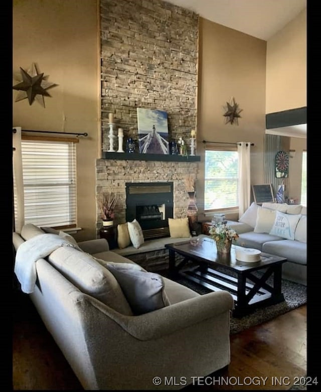 living room with a fireplace, dark wood-type flooring, and a high ceiling