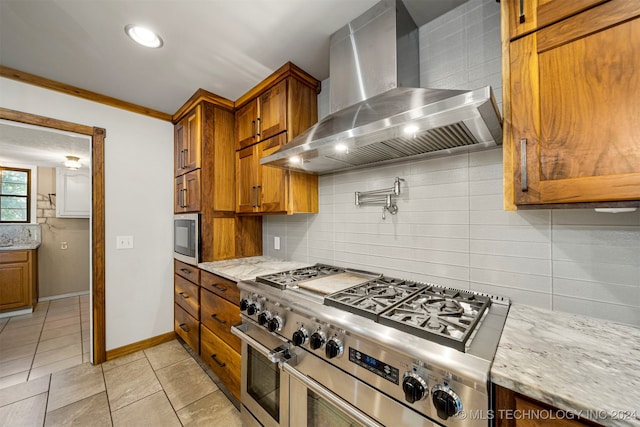 kitchen featuring crown molding, wall chimney exhaust hood, decorative backsplash, appliances with stainless steel finishes, and light stone counters