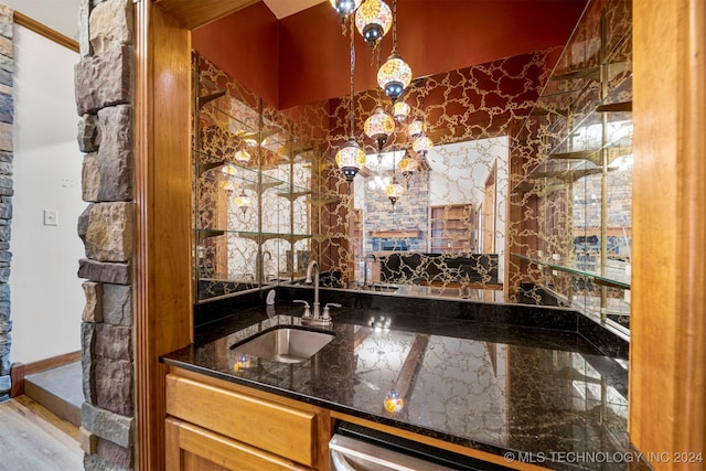 bar with sink, dark stone counters, and hardwood / wood-style flooring