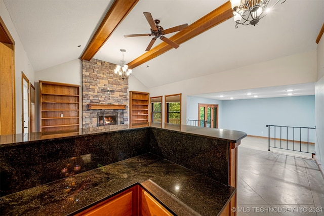 kitchen featuring a fireplace, dark stone counters, decorative light fixtures, a notable chandelier, and beamed ceiling