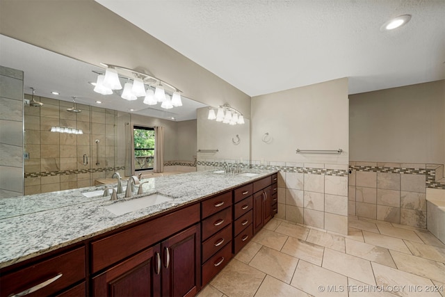 bathroom featuring vanity, a shower with door, tile patterned floors, tile walls, and a textured ceiling