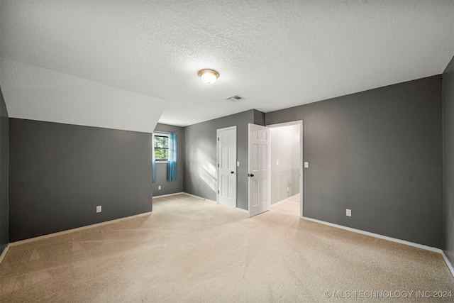 additional living space with lofted ceiling, light colored carpet, and a textured ceiling