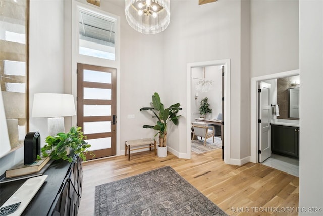 foyer with light wood-type flooring, a high ceiling, and a chandelier