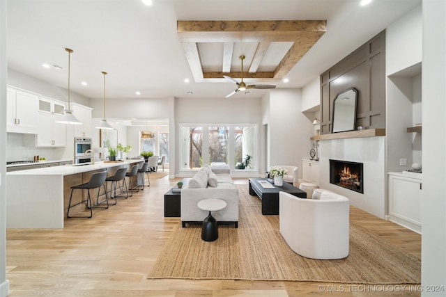 living room featuring ceiling fan, beam ceiling, and light wood-type flooring