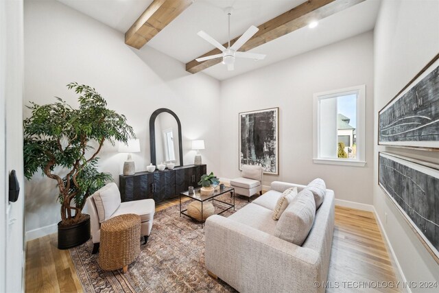 living room with ceiling fan, hardwood / wood-style floors, and beamed ceiling