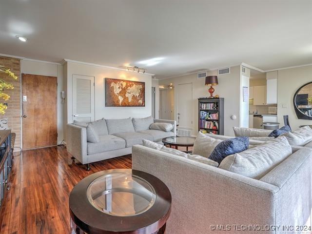 living room featuring ornamental molding and dark wood-type flooring