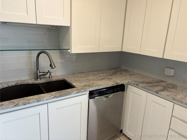 kitchen with light stone countertops, sink, white cabinets, and stainless steel dishwasher