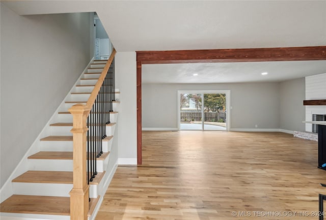 staircase featuring hardwood / wood-style flooring and a brick fireplace