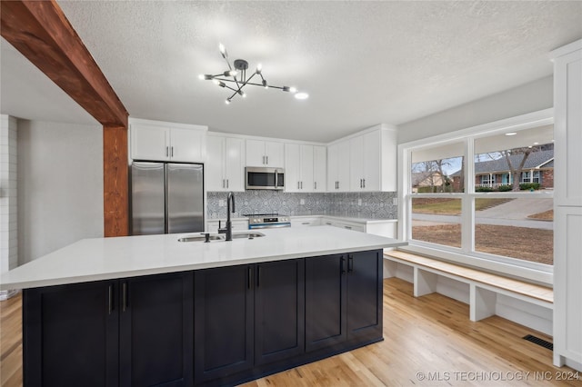 kitchen featuring white cabinets, appliances with stainless steel finishes, an island with sink, and sink