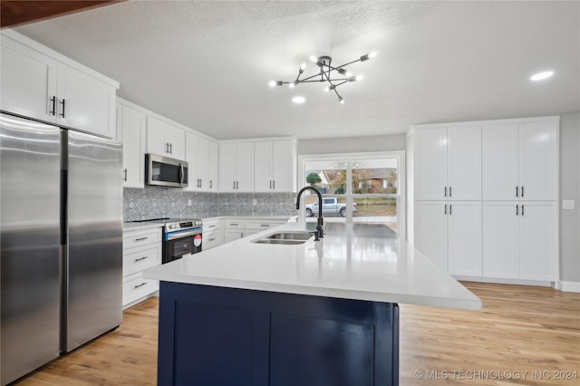 kitchen featuring white cabinets, sink, light hardwood / wood-style flooring, an island with sink, and appliances with stainless steel finishes