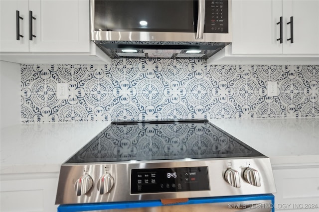 kitchen featuring white cabinetry, decorative backsplash, stove, and light stone counters