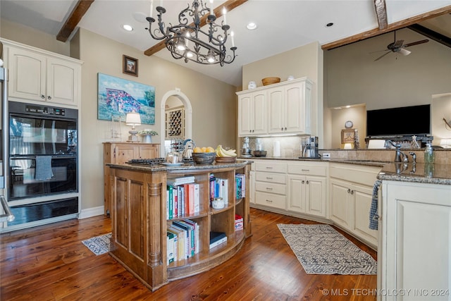 kitchen with white cabinets, beam ceiling, kitchen peninsula, and black double oven