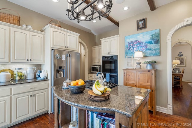 kitchen featuring dark hardwood / wood-style floors, a kitchen island, dark stone countertops, and appliances with stainless steel finishes