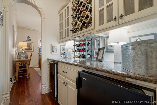 bar featuring beverage cooler, crown molding, dark wood-type flooring, stone countertops, and cream cabinetry