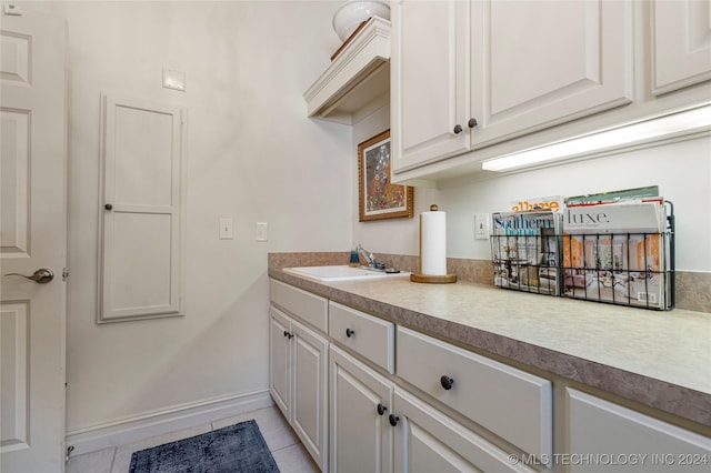 kitchen featuring white cabinets, light tile patterned flooring, and sink