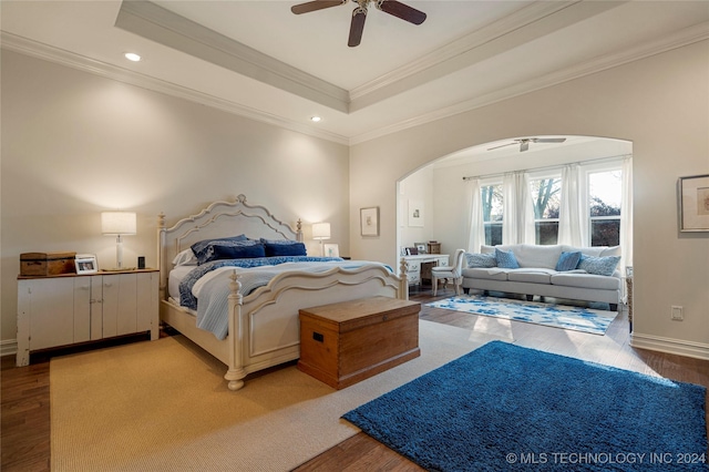 bedroom featuring hardwood / wood-style floors, ceiling fan, a raised ceiling, and crown molding