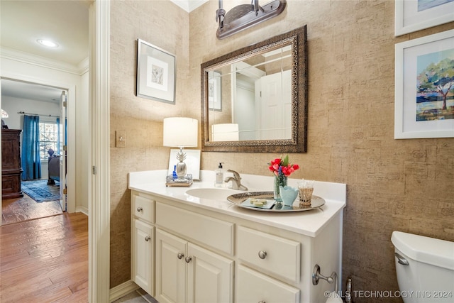 bathroom with wood-type flooring, vanity, toilet, and ornamental molding