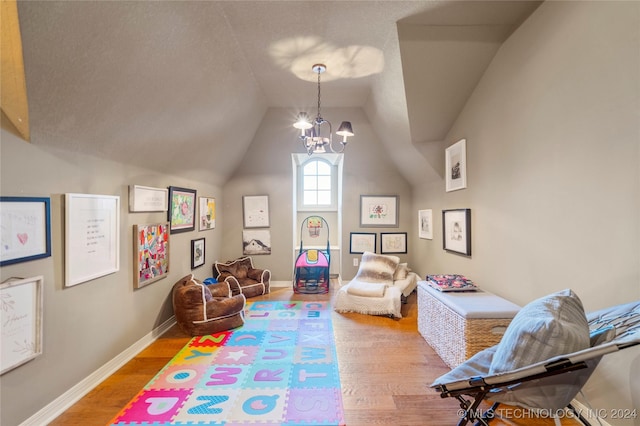 rec room with wood-type flooring, an inviting chandelier, and lofted ceiling