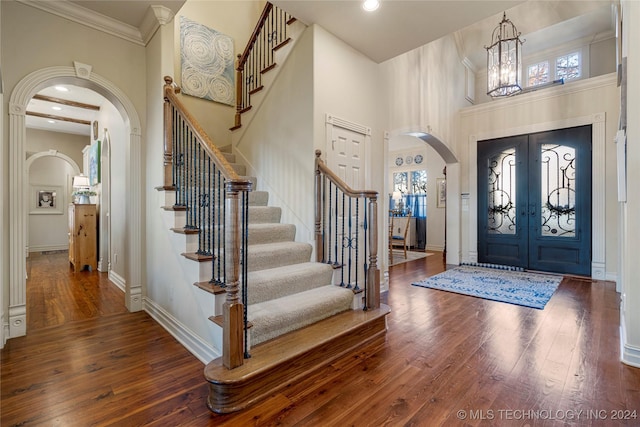 foyer featuring a high ceiling, french doors, dark wood-type flooring, and a notable chandelier