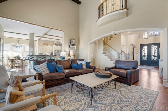 living room featuring dark hardwood / wood-style flooring, a towering ceiling, and french doors