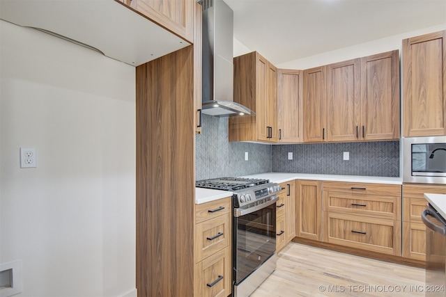 kitchen with decorative backsplash, light hardwood / wood-style flooring, wall chimney exhaust hood, and stainless steel appliances