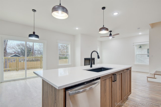 kitchen featuring stainless steel dishwasher, ceiling fan, sink, light hardwood / wood-style floors, and an island with sink