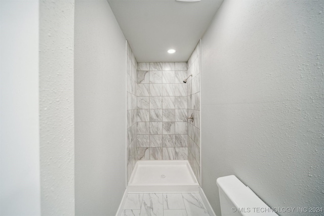 bathroom featuring tiled shower and toilet