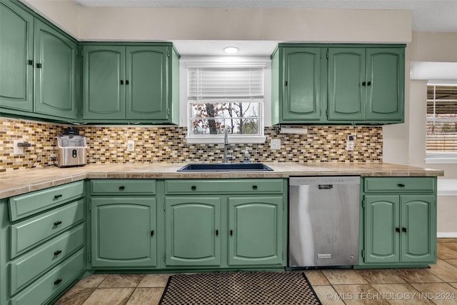 kitchen featuring green cabinetry, dishwasher, backsplash, light countertops, and a sink