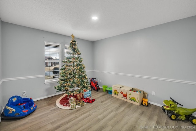 game room featuring a textured ceiling, baseboards, wood finished floors, and recessed lighting