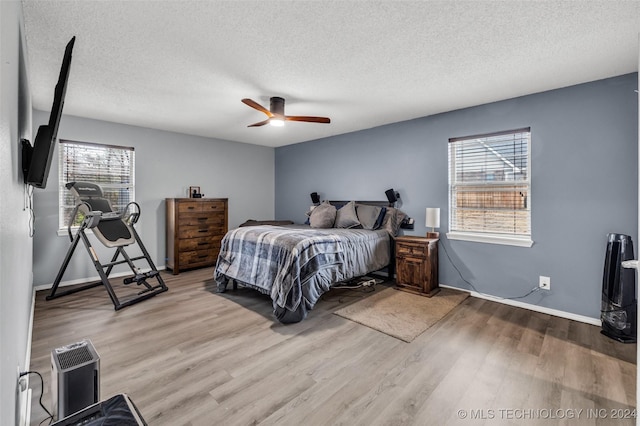 bedroom with multiple windows, light hardwood / wood-style flooring, and a textured ceiling