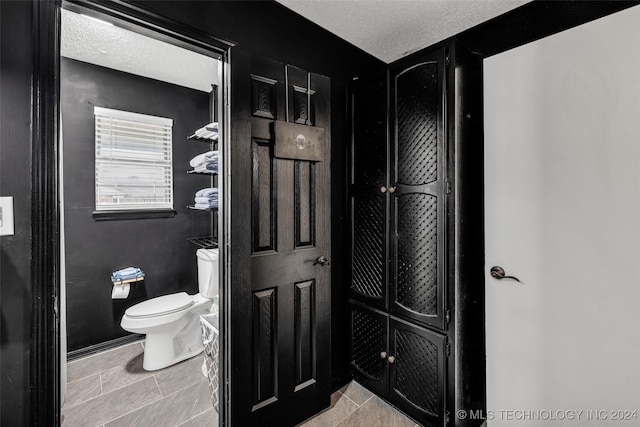 bathroom featuring tile patterned floors, a textured ceiling, and toilet