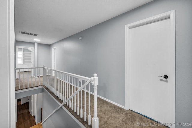 corridor featuring visible vents, carpet flooring, an upstairs landing, and baseboards