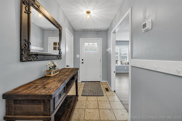 foyer with visible vents, a textured ceiling, and baseboards