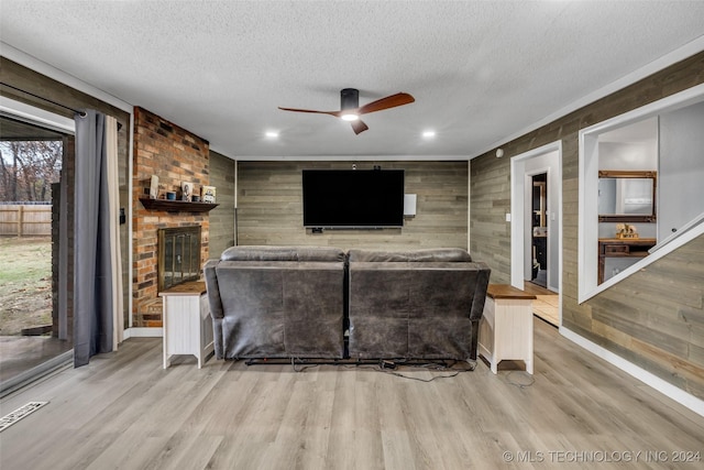 living room with a fireplace, a textured ceiling, and light wood-type flooring