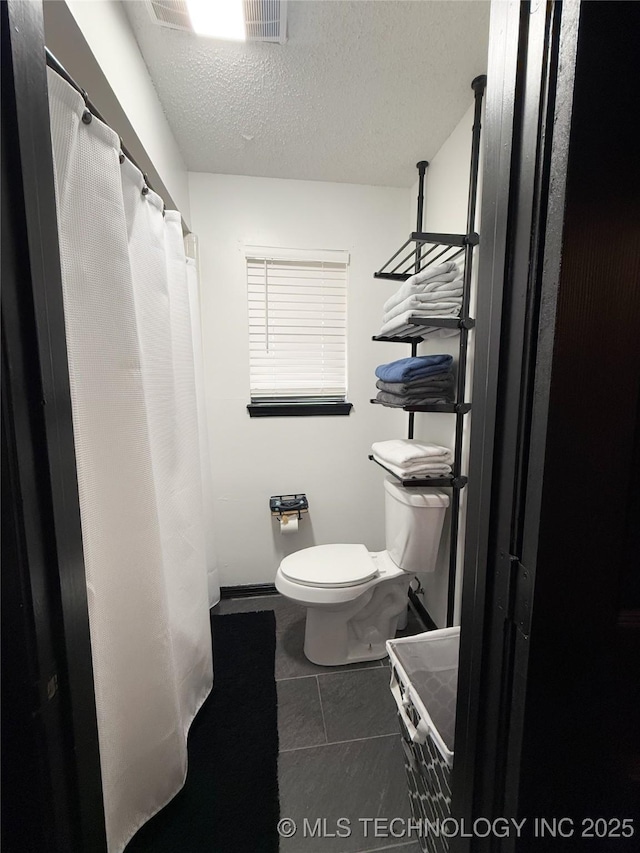 bathroom with a textured ceiling, tile patterned floors, and toilet